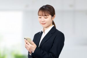 スマホをもって操作をしている女子大学生